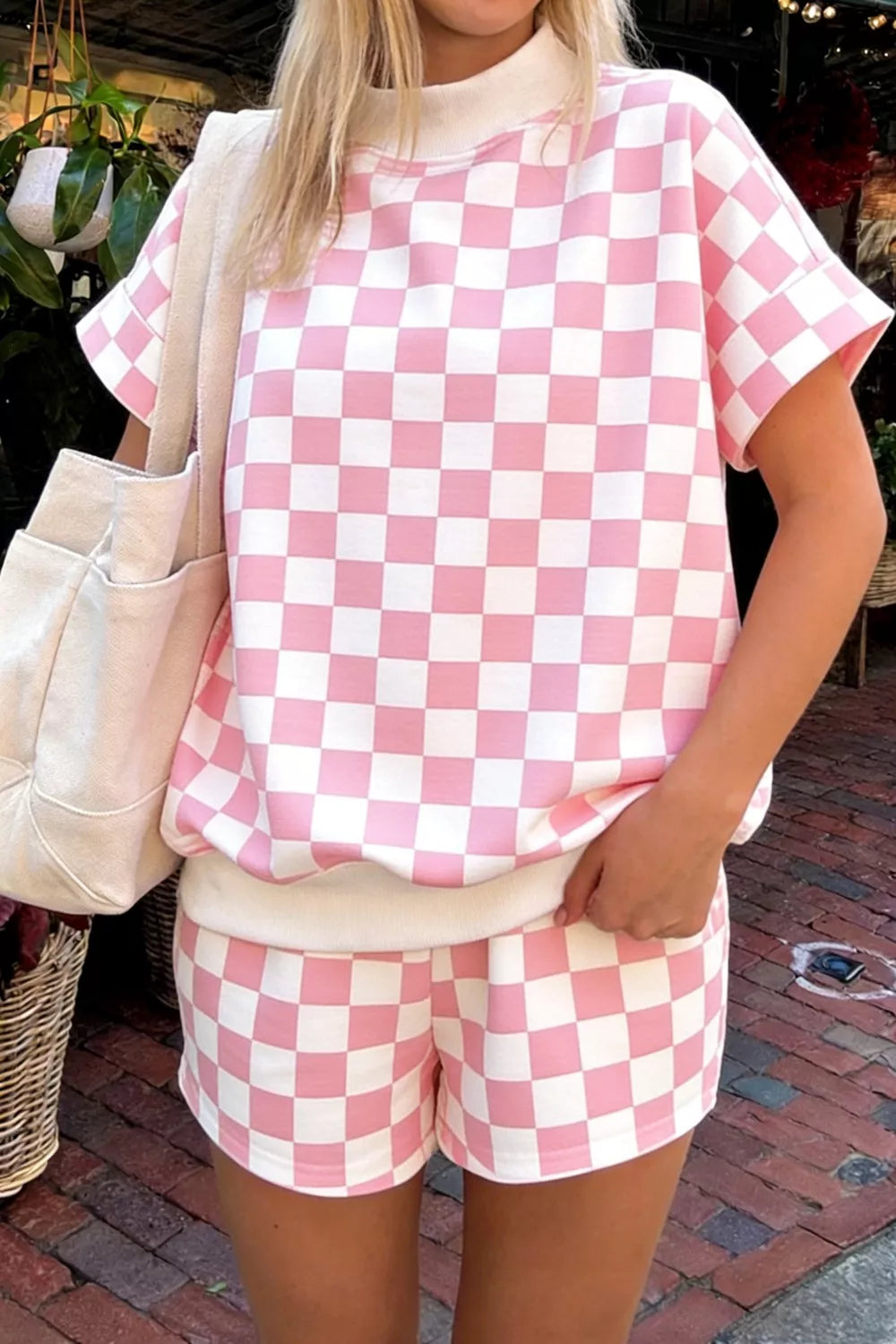 Front view of women's two-piece checkered luxury lounge set with a subtle geometric textured knit short-sleeve shirt and matching drawstring shorts in classic pink.