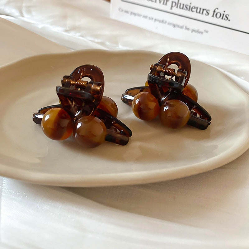 A luxury high-shine tortoise shell acrylic hair claw clip displayed on a natural linen surface for a premium travel spa aesthetic.