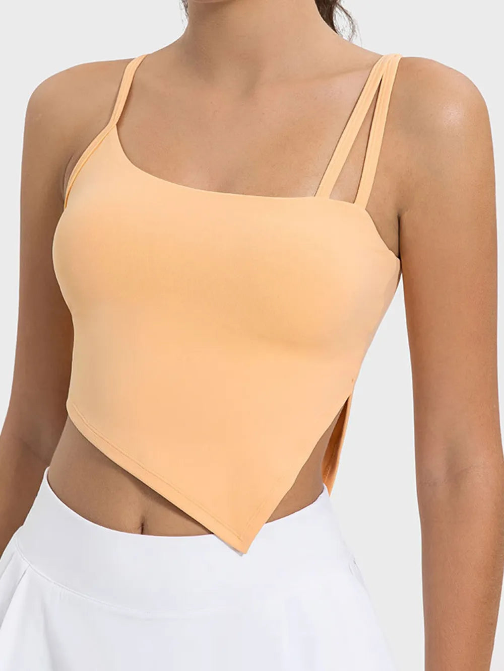 Woman wearing a peach-colored strappy top against a white background