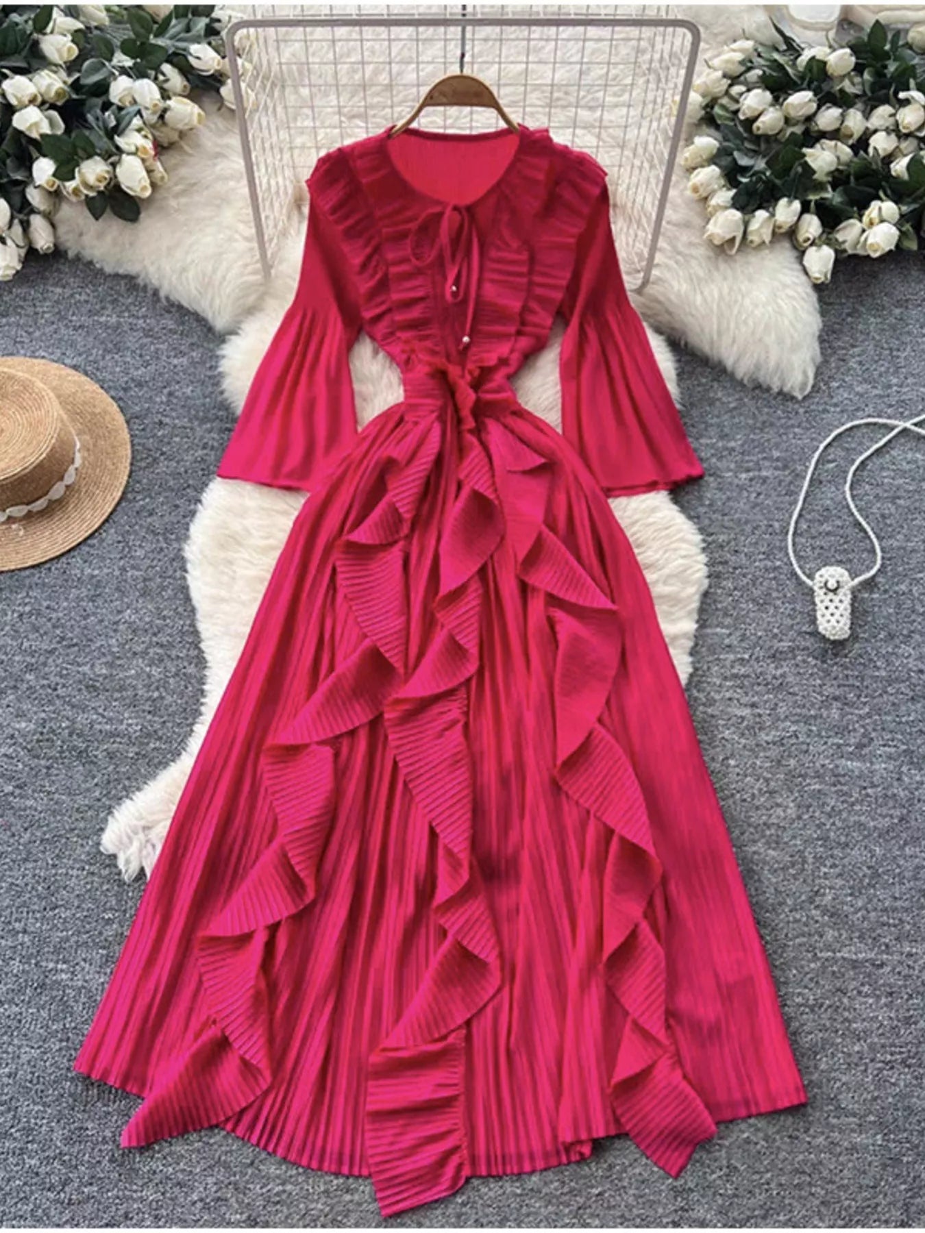 Red ruffled dress on a hanger with decorative elements on a gray surface