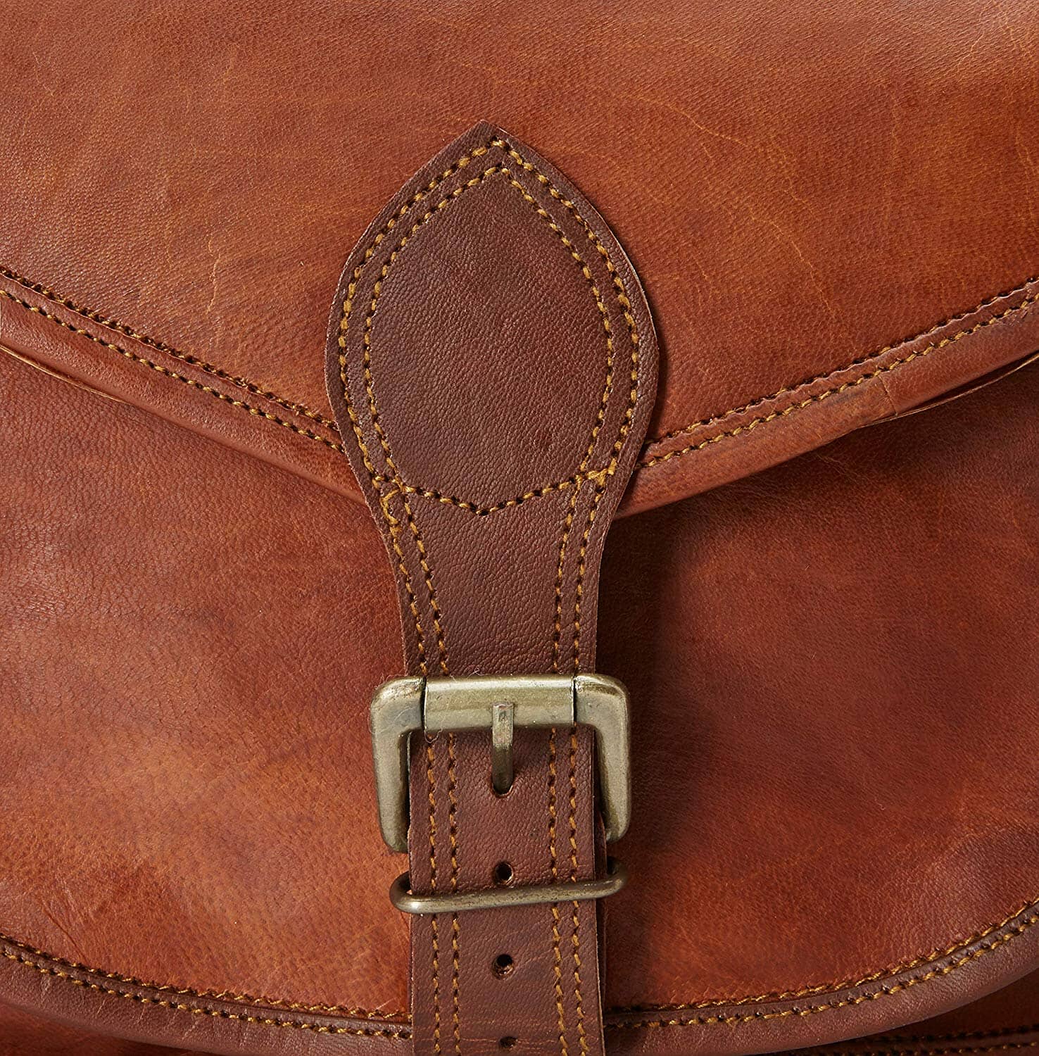 Close-up of a brown leather bag with a strap and buckle