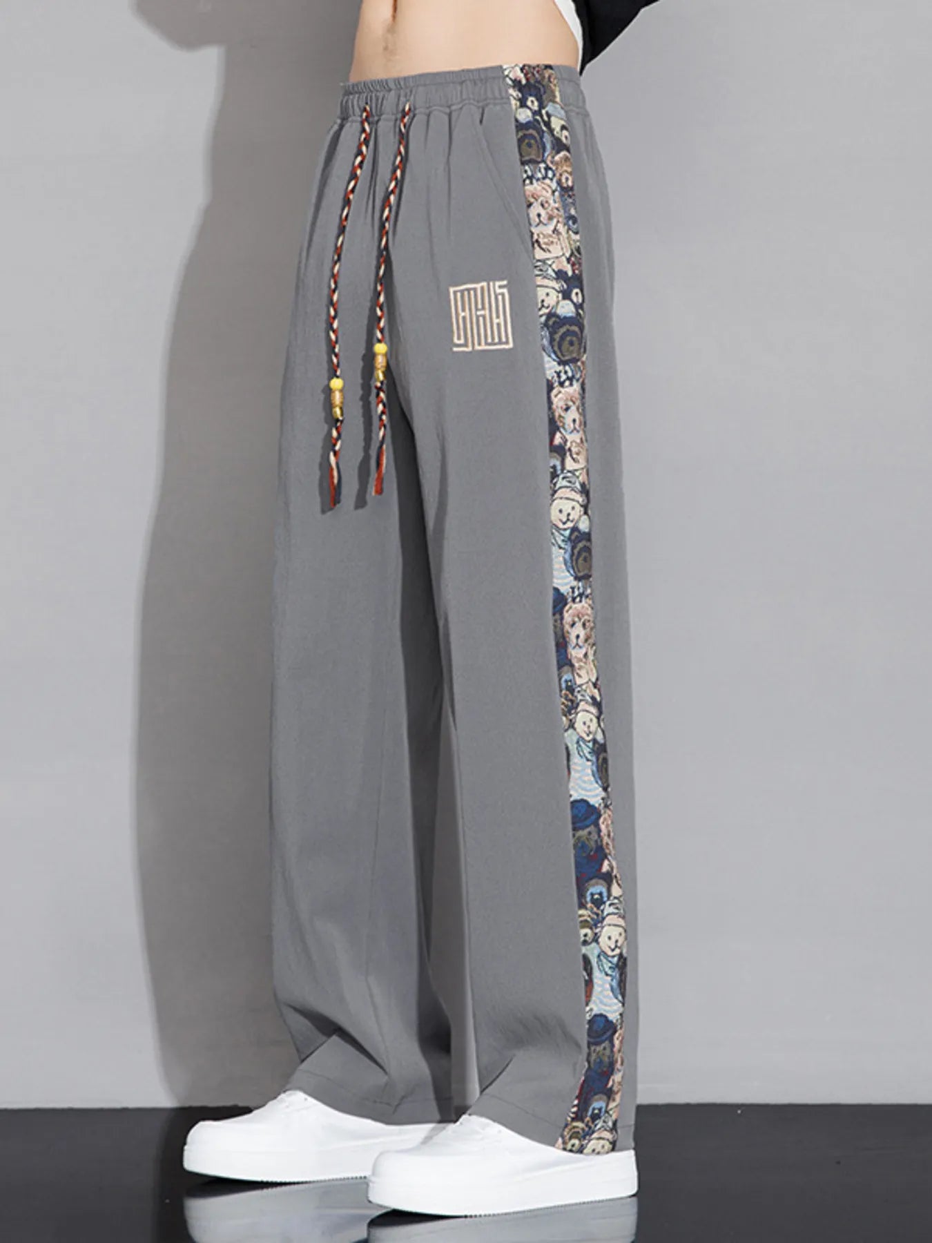 Gray pants with floral side panels and a brand logo on a gray background