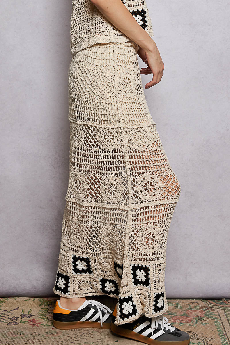 Person wearing a long, patterned crochet skirt with a neutral background