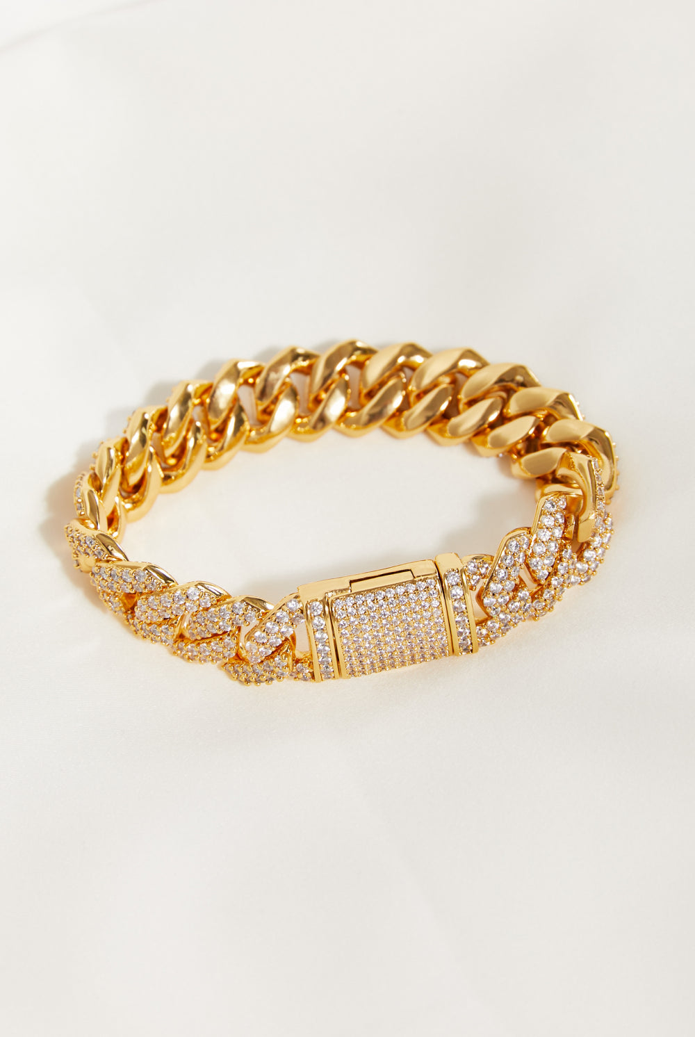 Gold chain bracelet with diamond accents on a light beige background