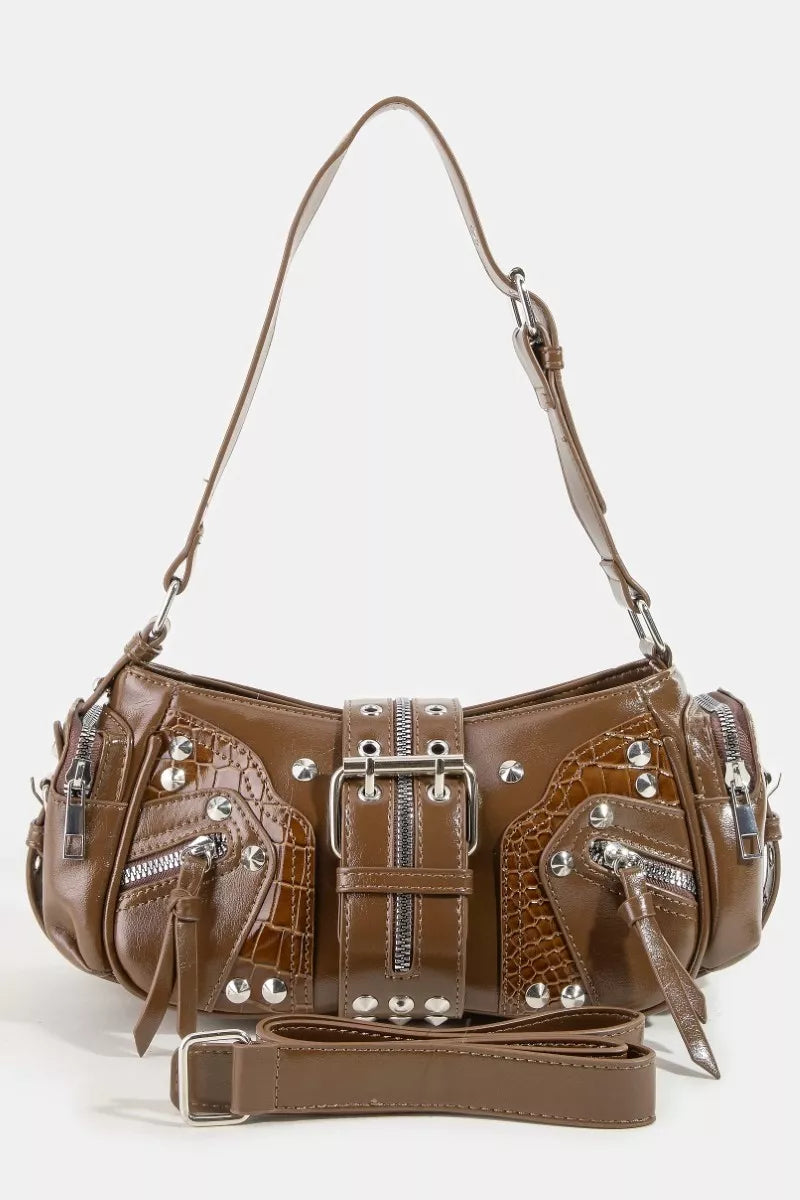 A detailed close-up view of the Stella bag, showcasing the beautiful texture of the genuine leather and the precise, high-shine finish of the hardware studs. Brown handbag.