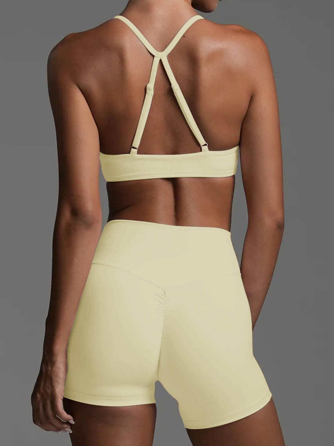 Person wearing a light yellow sports bra and shorts on a gray background
