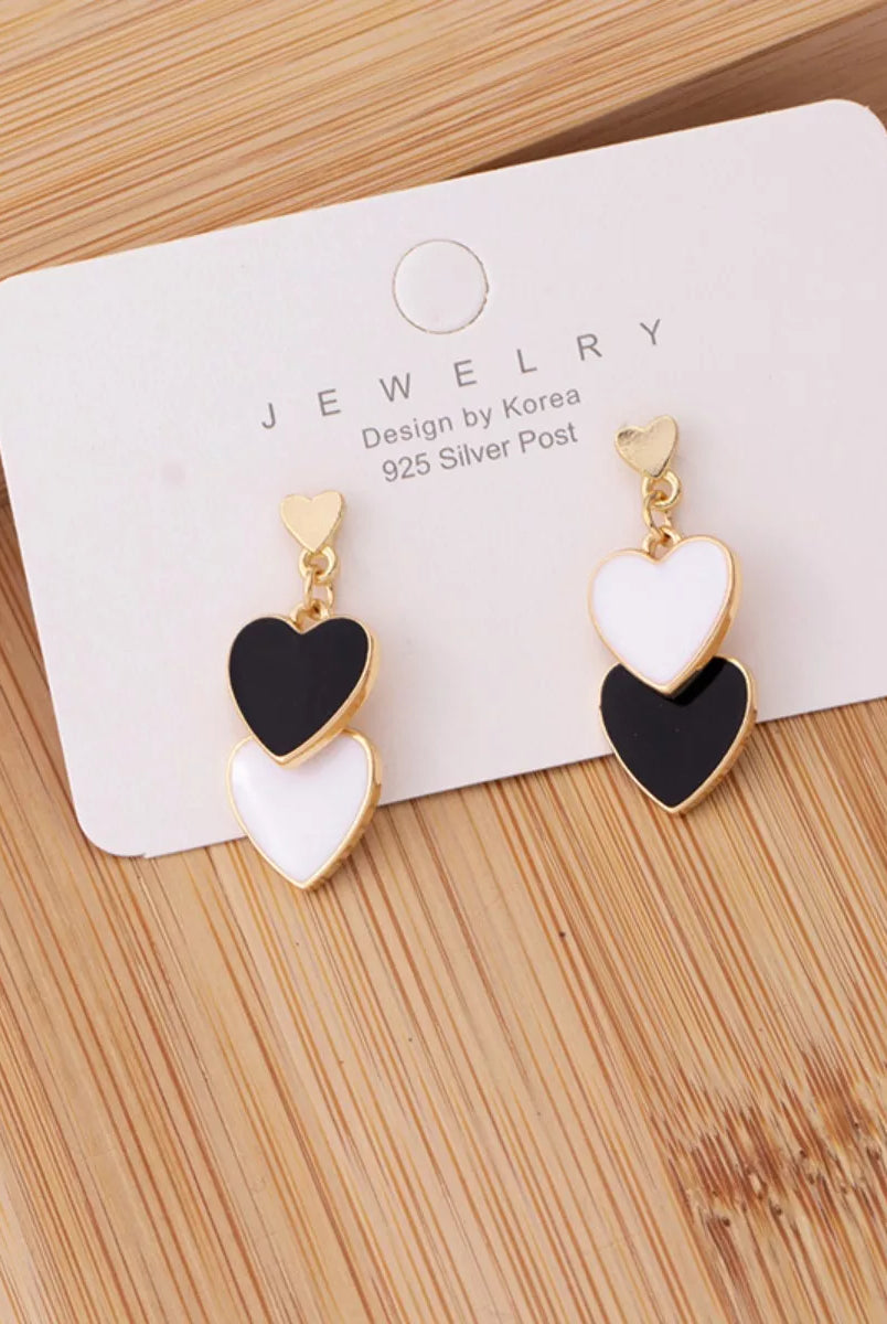 Heart-shaped earrings on a jewelry card with 'Design by Korea' text on a wooden surface.