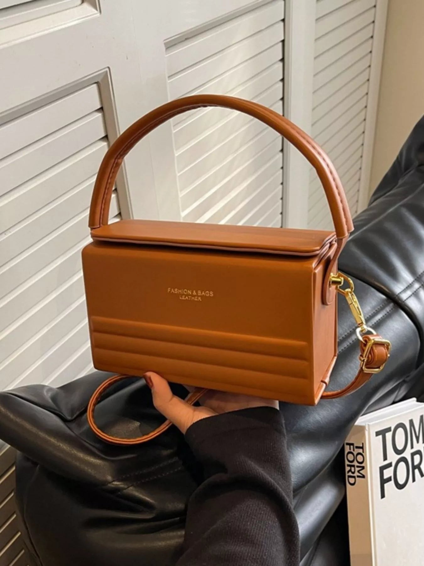 Brown handbag held by a person with a blurred background
