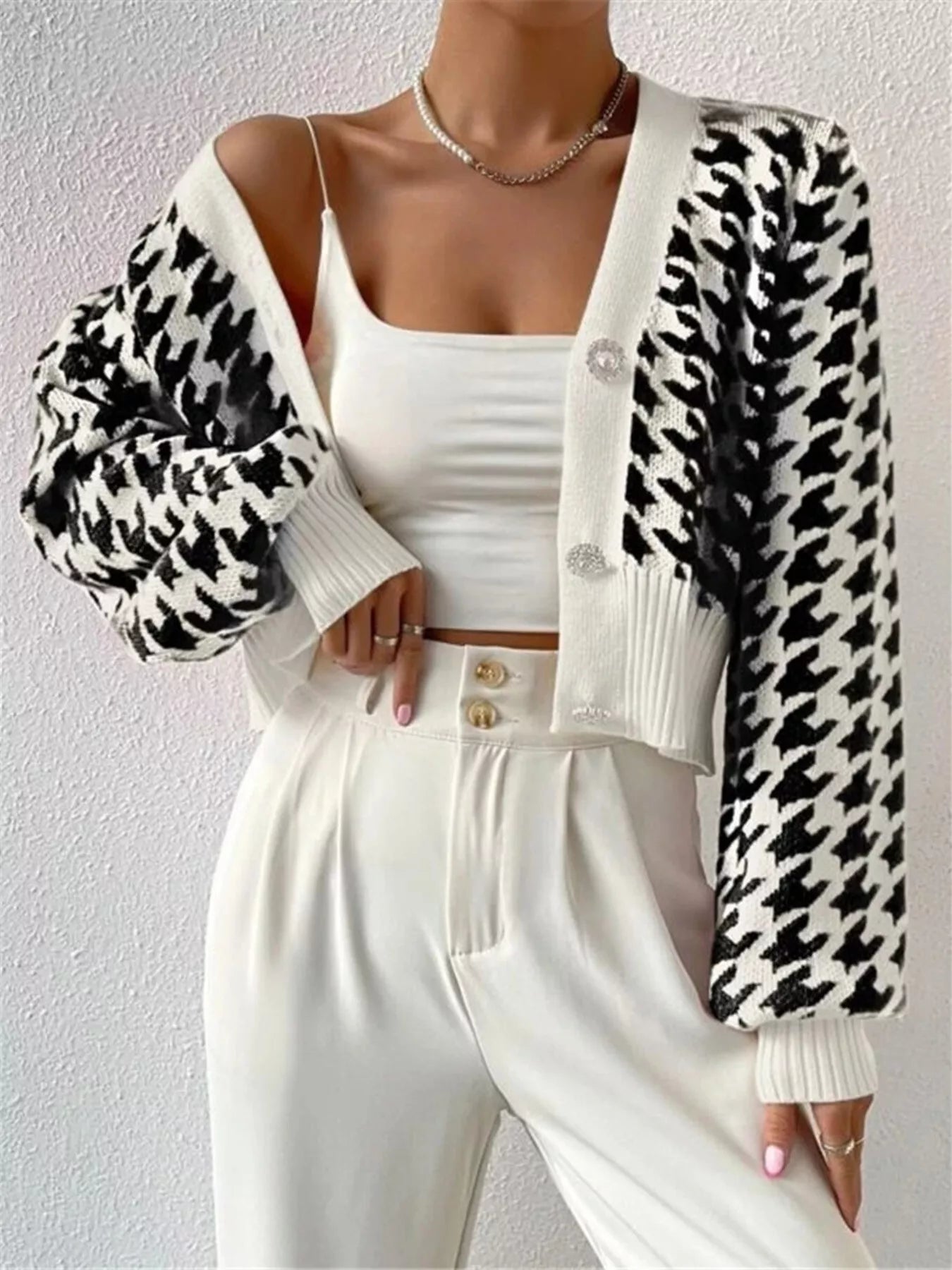 The Houndstooth V-Neck Button Up Cardigan features a classic pattern and a tailored fit. It layers easily over shirts or tees with its flattering V-neck and offers adjustable comfort with a button-up front. Durable and stylish, it’s suitable for both work and casual wear.