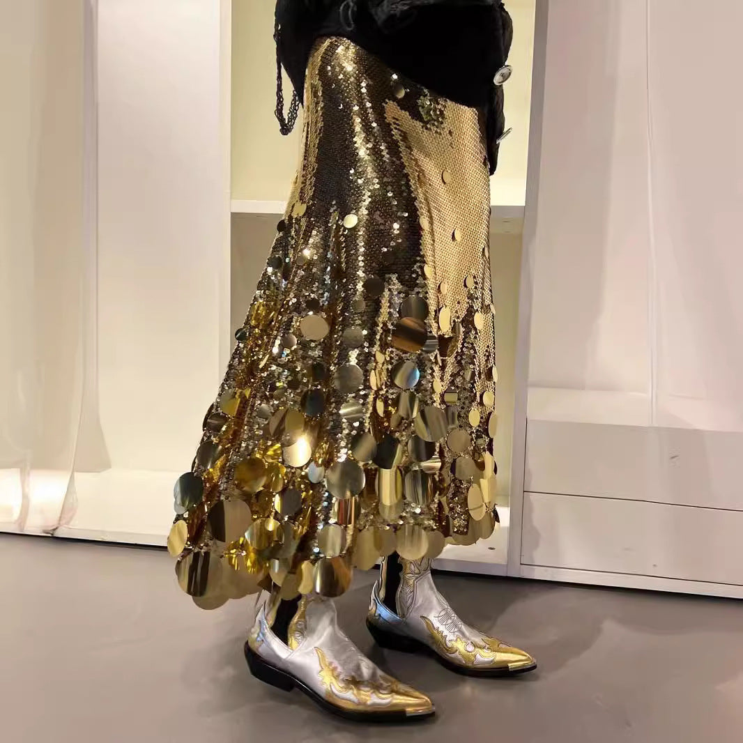 Person wearing a gold sequin skirt and silver boots in a room with white walls.