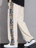 Beige pants with a colorful side stripe worn by a person, on a plain background