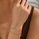 Gold bracelet with a star charm on a wrist against a neutral background