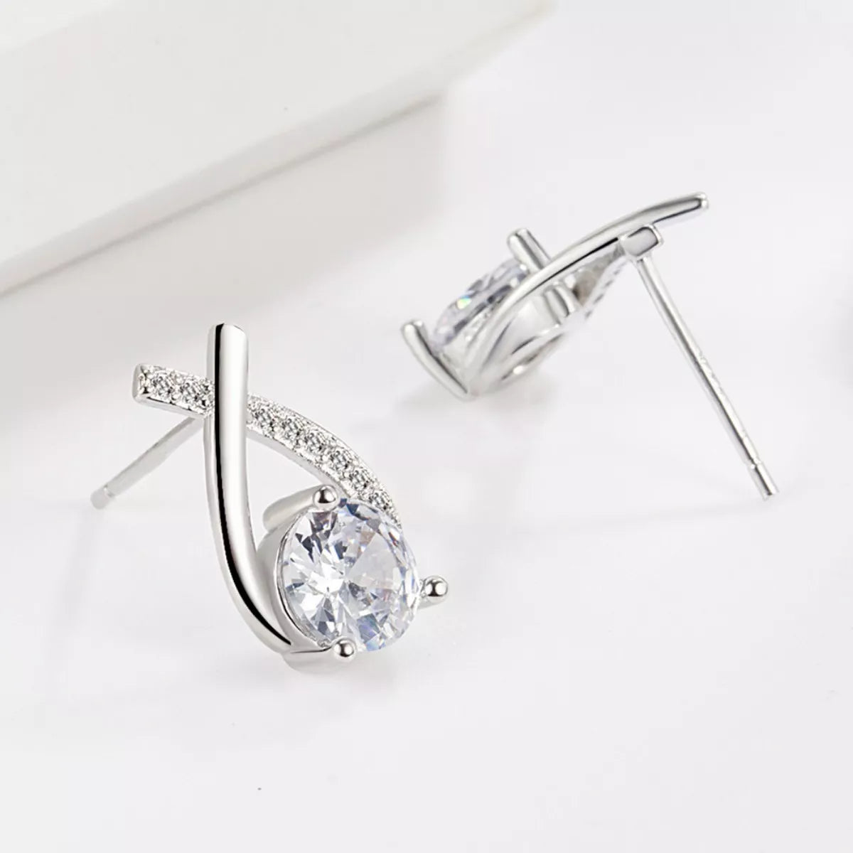 Silver earrings with clear gemstones on a light gray background