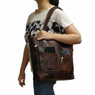 Person holding a brown leather bag with multiple pockets on a white background