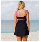Person wearing a black swimsuit with pink straps on a beach