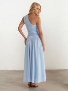 Woman wearing a light blue one-shoulder dress against a white background