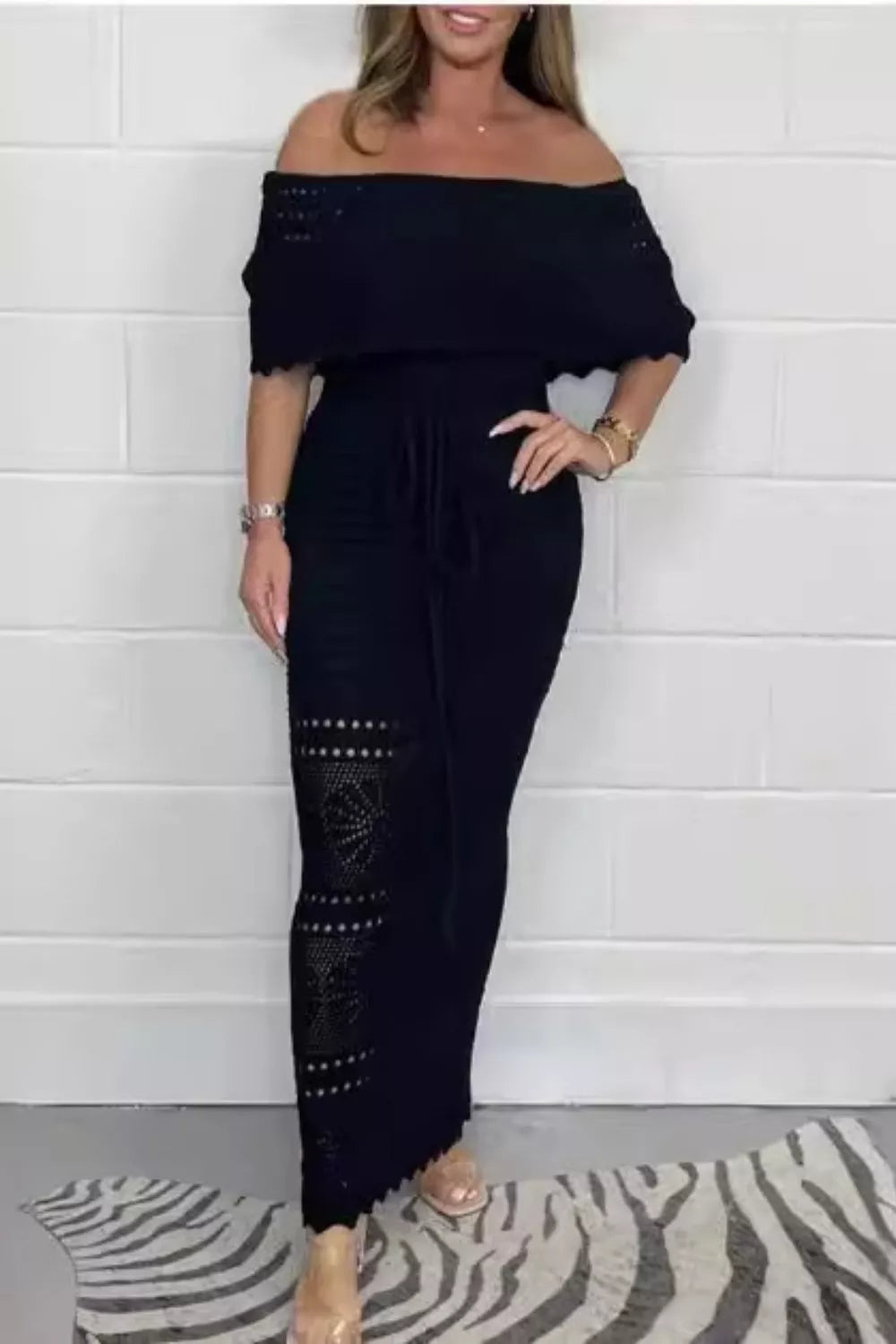 The Riviera Maxi dress showcasing the crochet off-the-shoulder neckline, detailed waist cutout, and elegant front-tie design. Black.