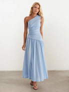 Woman wearing a light blue one-shoulder dress against a white background