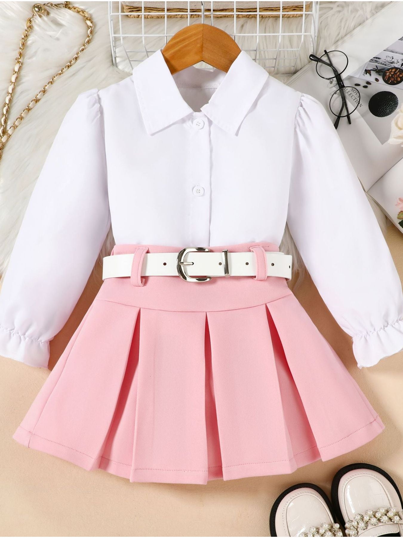 White blouse with pink pleated skirt on a beige surface