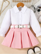 White blouse with pink pleated skirt on a beige surface