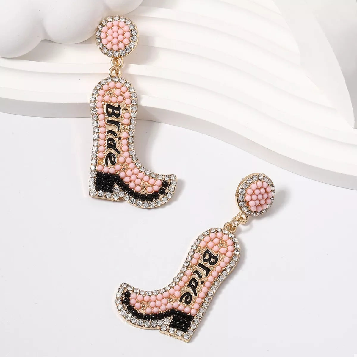 Pink cowboy boot earrings with 'Bride' text on a white background