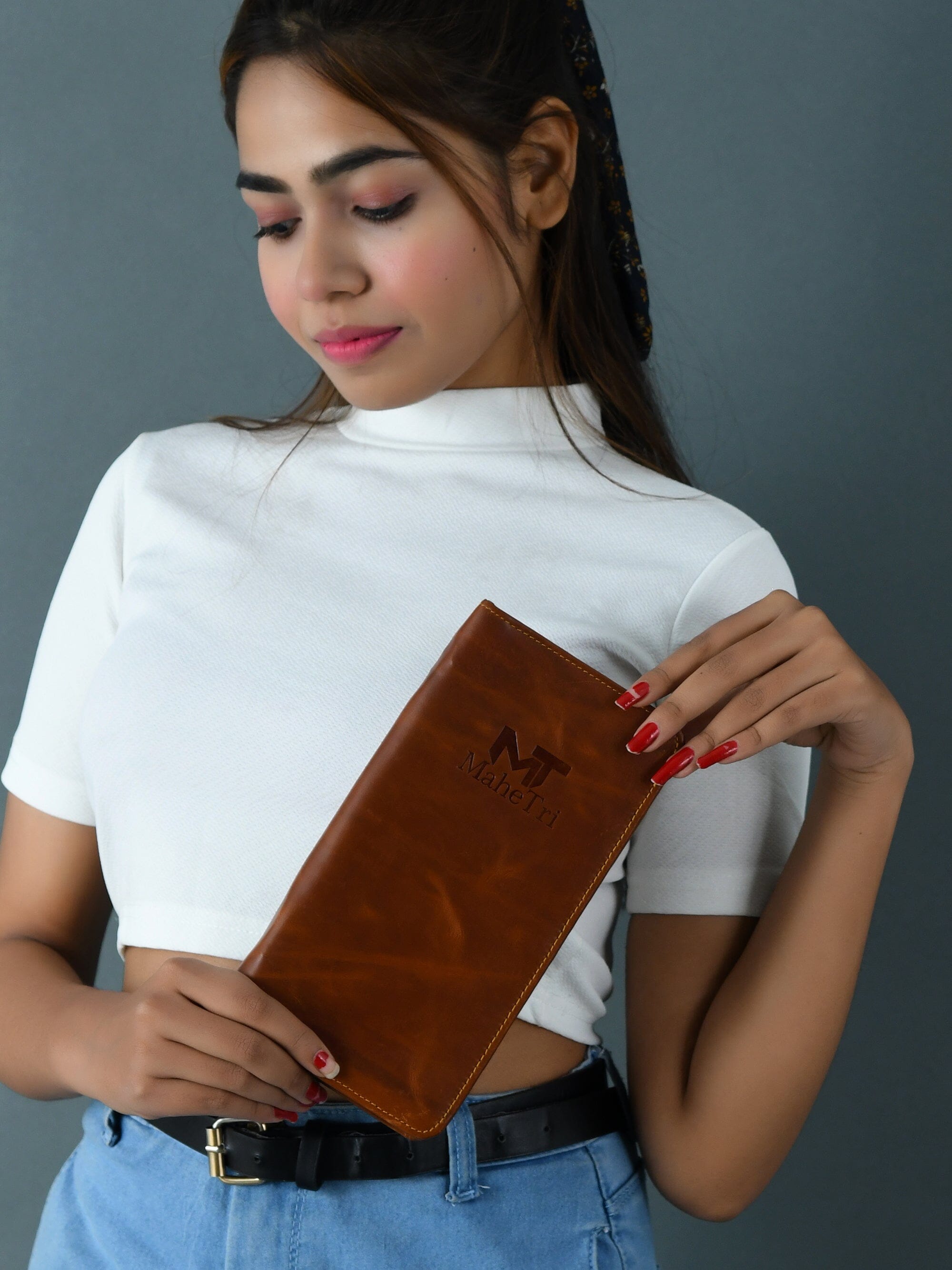Woman holding a brown clutch against a gray background