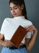Woman holding a brown clutch against a gray background