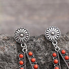 Silver earrings with coral beads on a stone surface