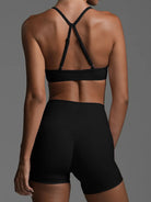 Person wearing a black sports bra and shorts on a gray background