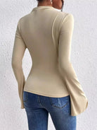 The Bell Sleeve Fitted T-Shirt features a structured mock neck and a tailored fit that contours the body for a sleek, sophisticated appearance. Its distinctive bell sleeves introduce graceful volume and movement, elevating this versatile piece for both professional and casual wardrobes. Designed with attention to detail, it balances modern style and timeless elegance.