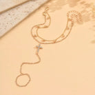 Gold necklace with a cross pendant on a beige surface