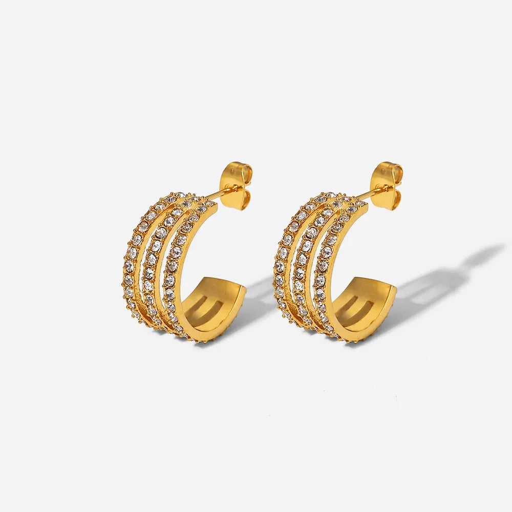 Gold hoop earrings with embedded stones on a light gray background