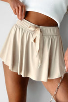 Beige skirt with a tie waist worn by a person on a plain background