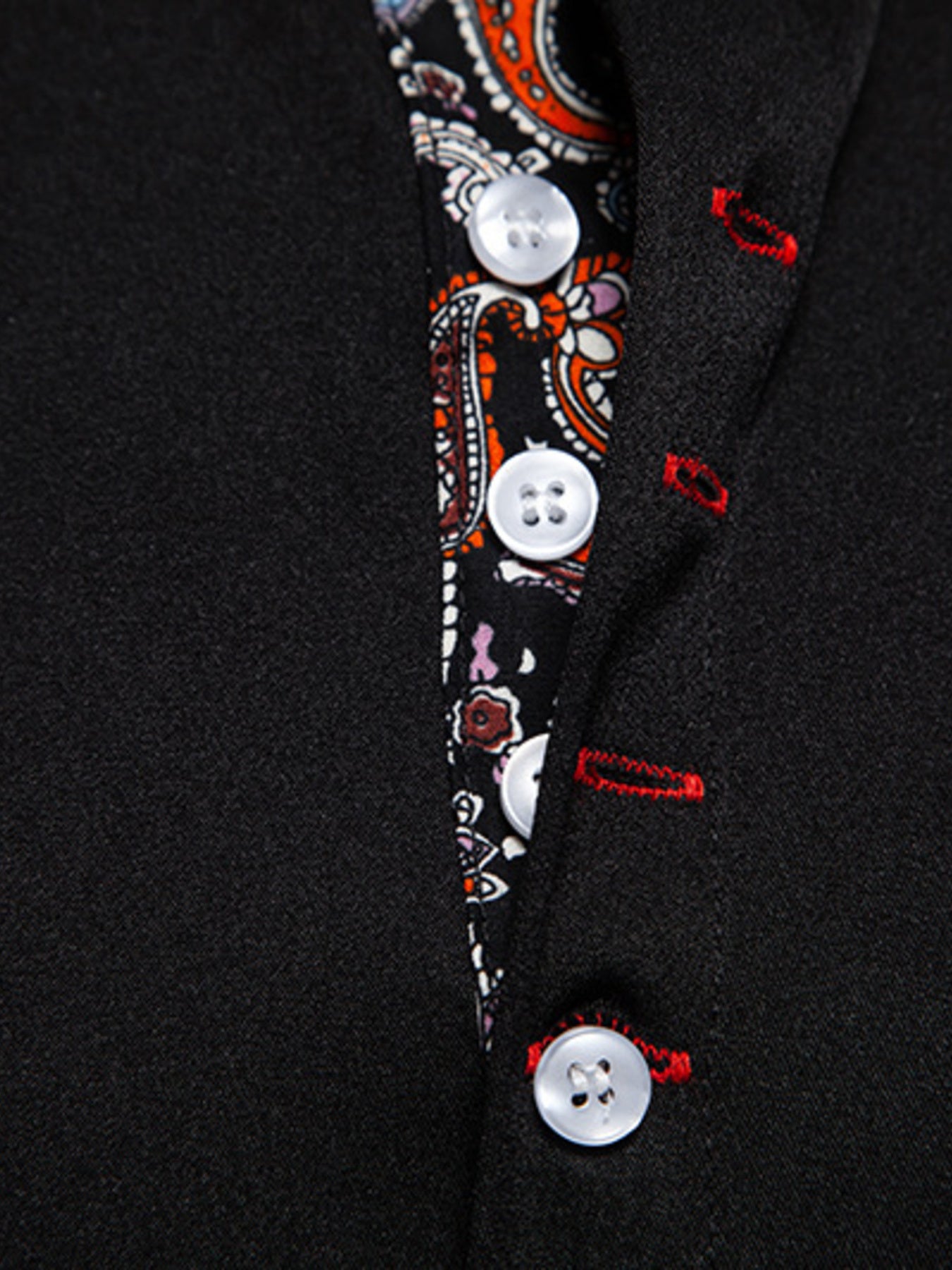 Close-up of a black coat with decorative buttons and patterns.