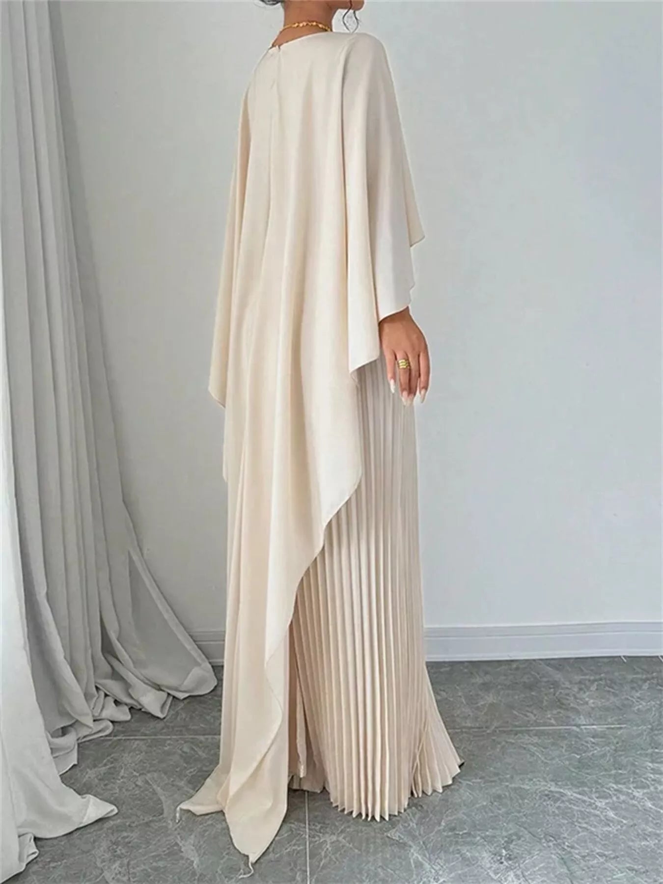 Beige pleated dress with long sleeves against a neutral background