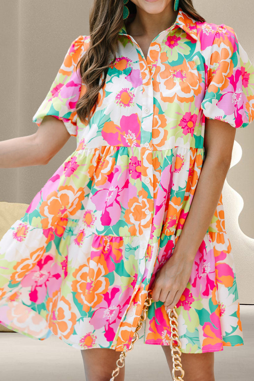A woman wearing a short sleeve mini dress with a colorful floral pattern on a pink background.