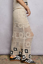 Person wearing a long, patterned crochet skirt with a neutral background