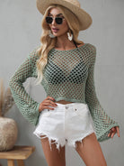 Woman wearing a green mesh top and white shorts with a straw hat and sunglasses on a gray background