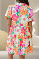 Back view of floral tiered mini dress with short puff sleeves and pink, orange, and green print.