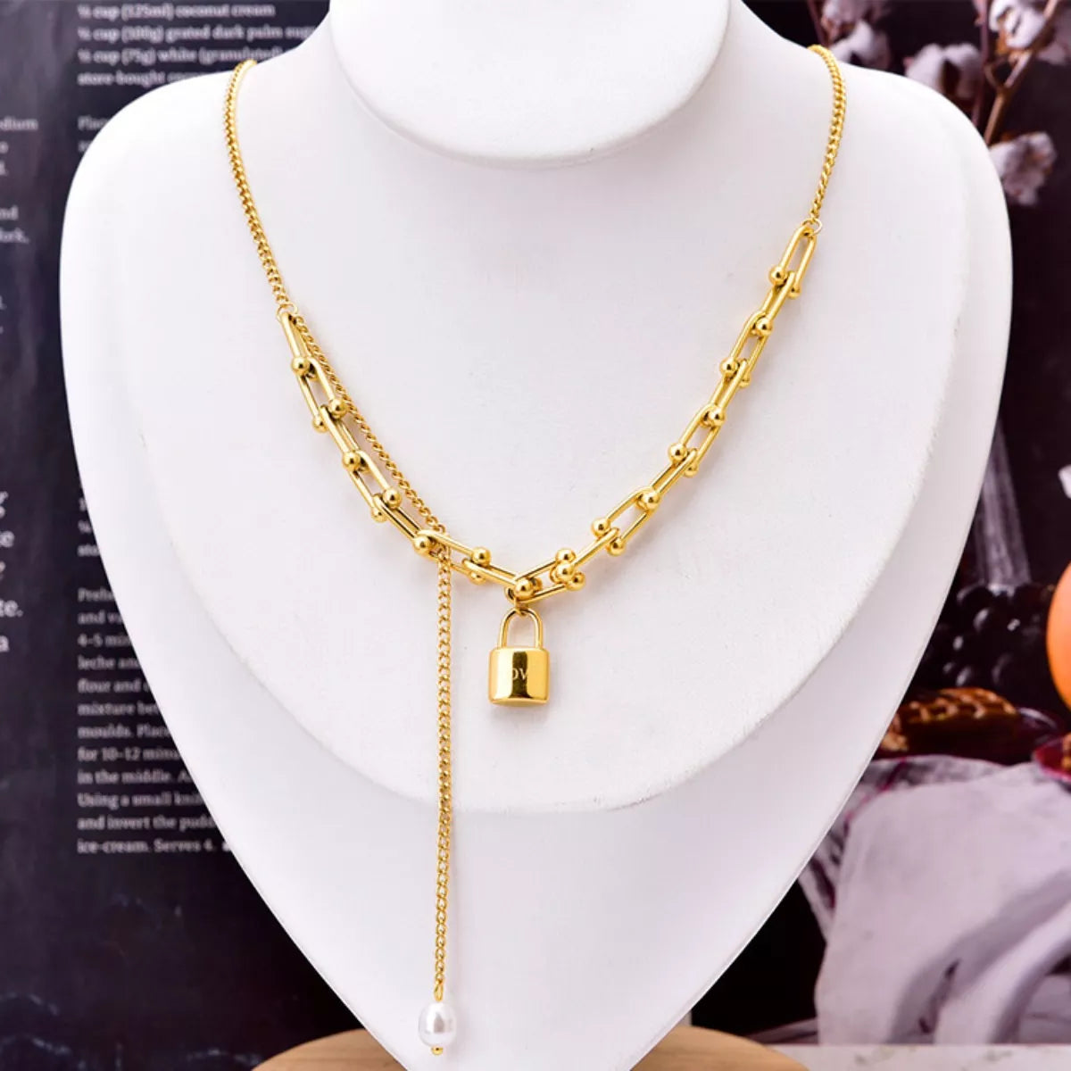 Gold chain necklace with a lock pendant on a mannequin bust.