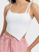 Person wearing a white tank top and pink pants on a plain background