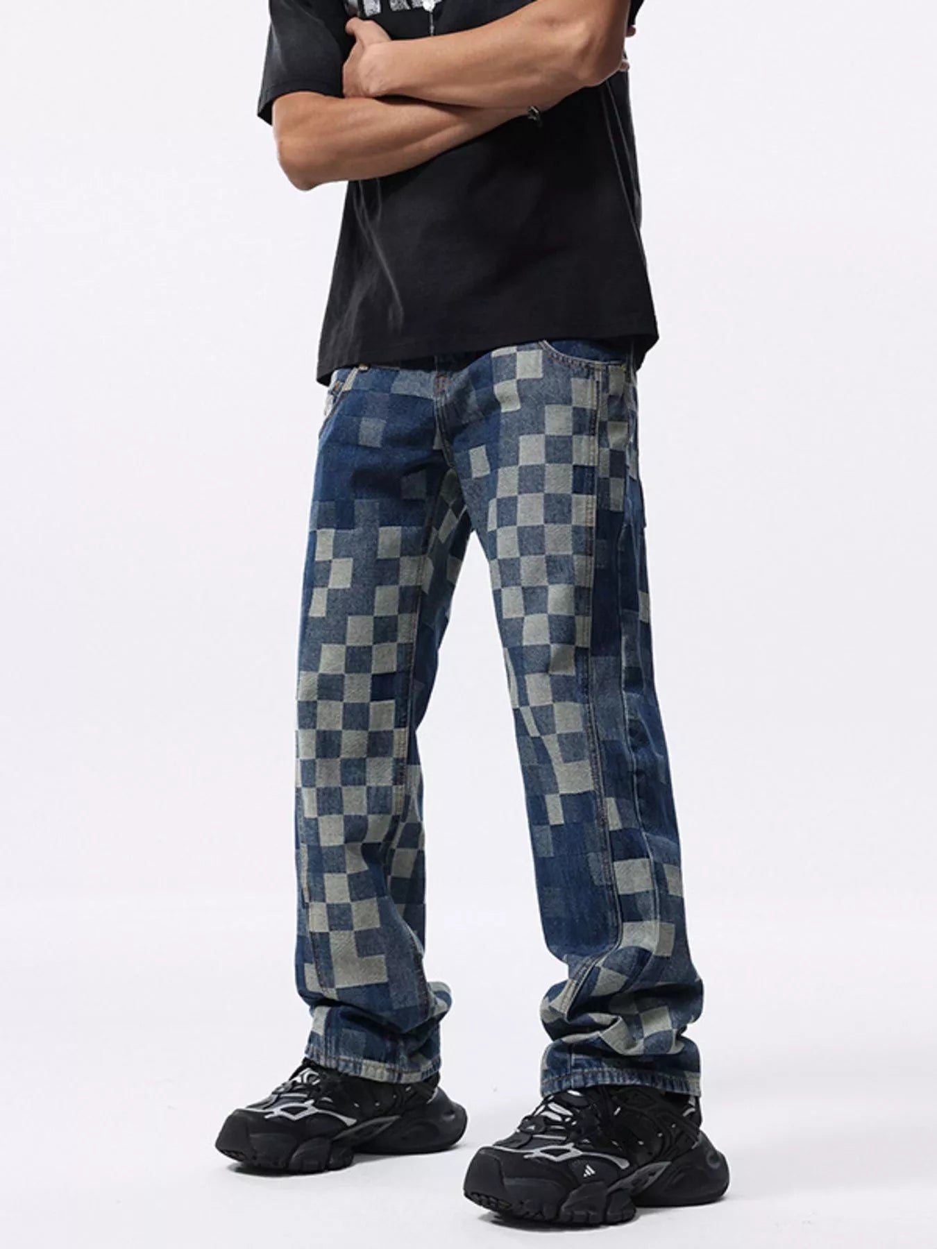 Person wearing checkered jeans and black shoes on a white background