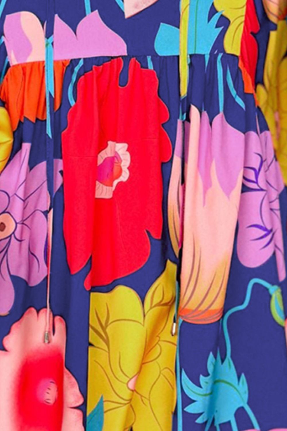 Close-up of floral cotton mini dress showing colorful blooms on a navy background, neckline ties, and gathered seam.