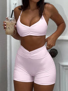 Person wearing a pink sports bra and shorts set, holding an iced coffee.