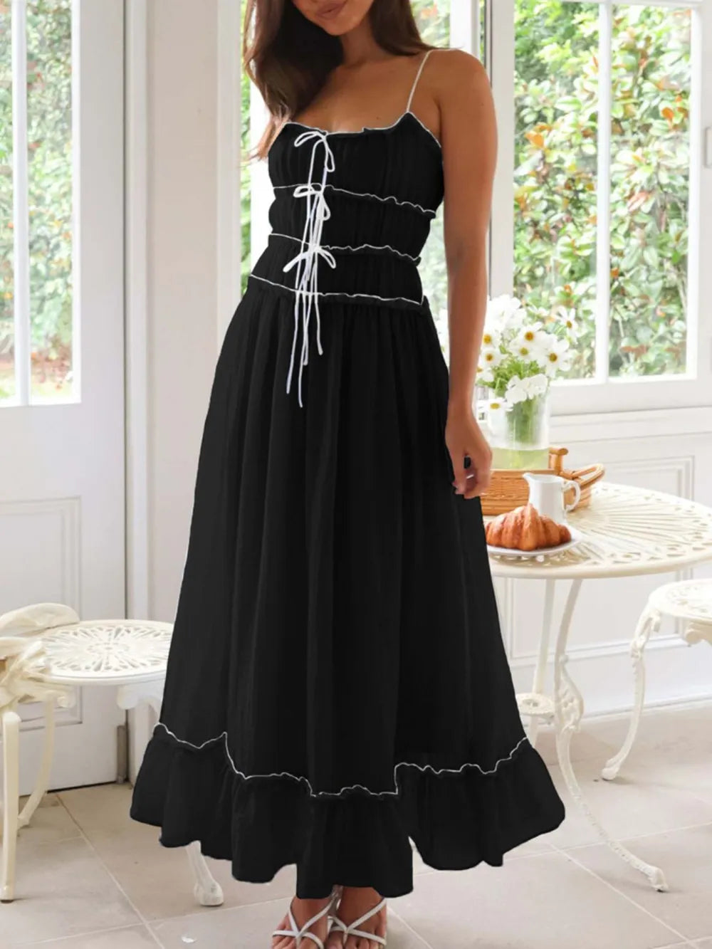 Woman wearing a black dress with white trim in a bright room.