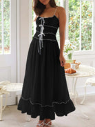 Woman wearing a black dress with white trim in a bright room.