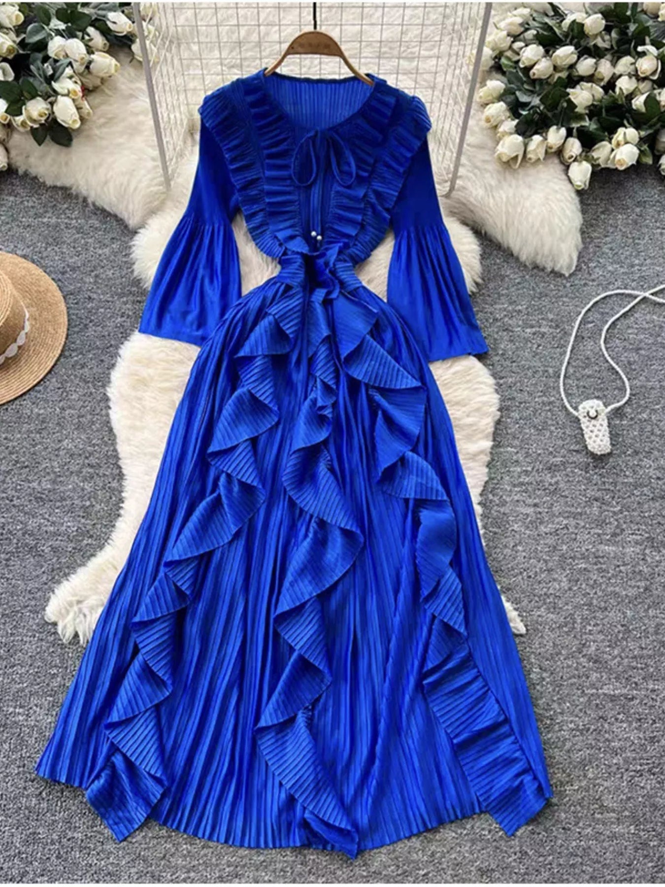 Blue ruffled dress on a hanger with decorative elements in the background