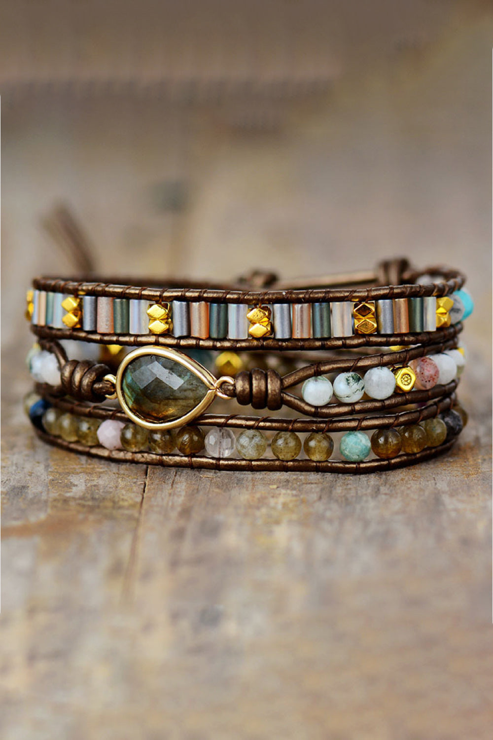 Multistrand beaded bracelet with a central gold accent on a wooden surface