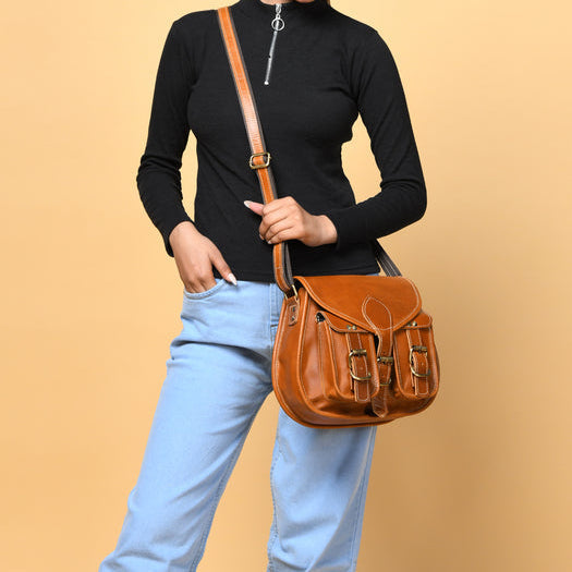 Person holding a brown leather satchel bag against a beige background