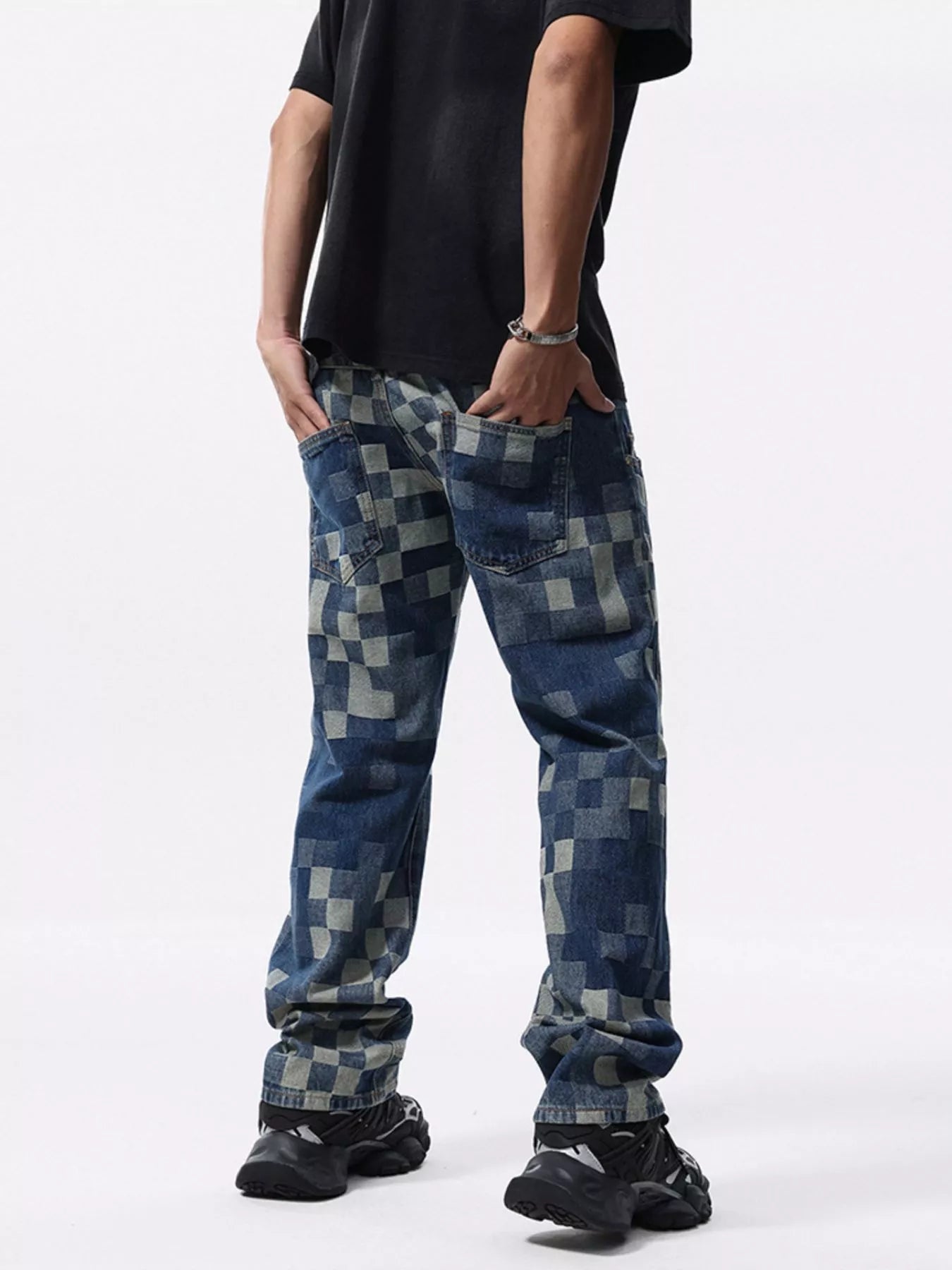 Person wearing checkered denim pants with hands in back pockets on a white background
